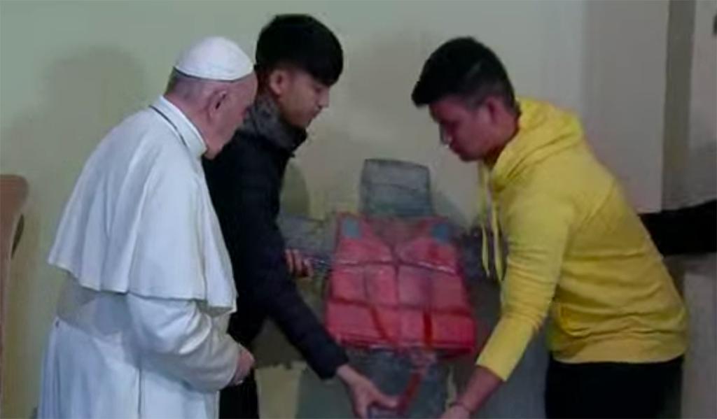 Pope Francis and the refugees from Lesbos unveiling the cross of migrants: