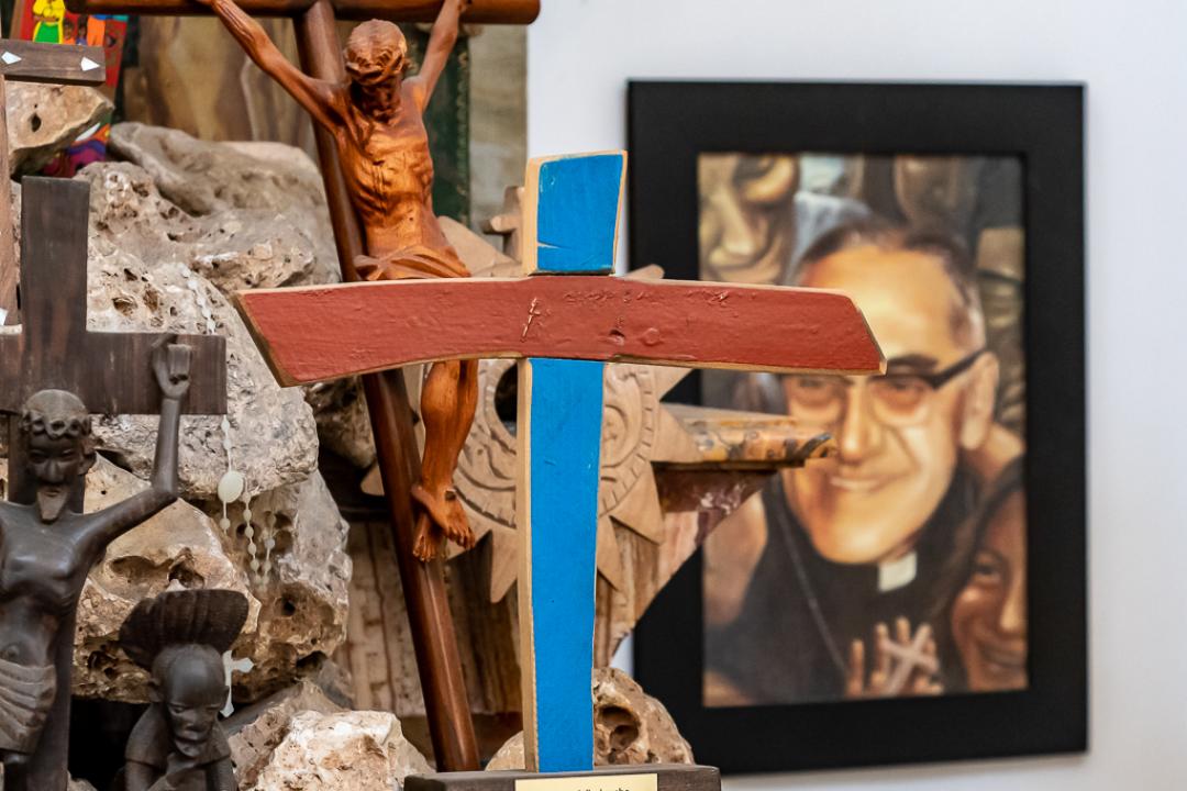 Cruz de Lampedusa de la capilla de las cruces. Al fondo, retrato de Óscar Romero